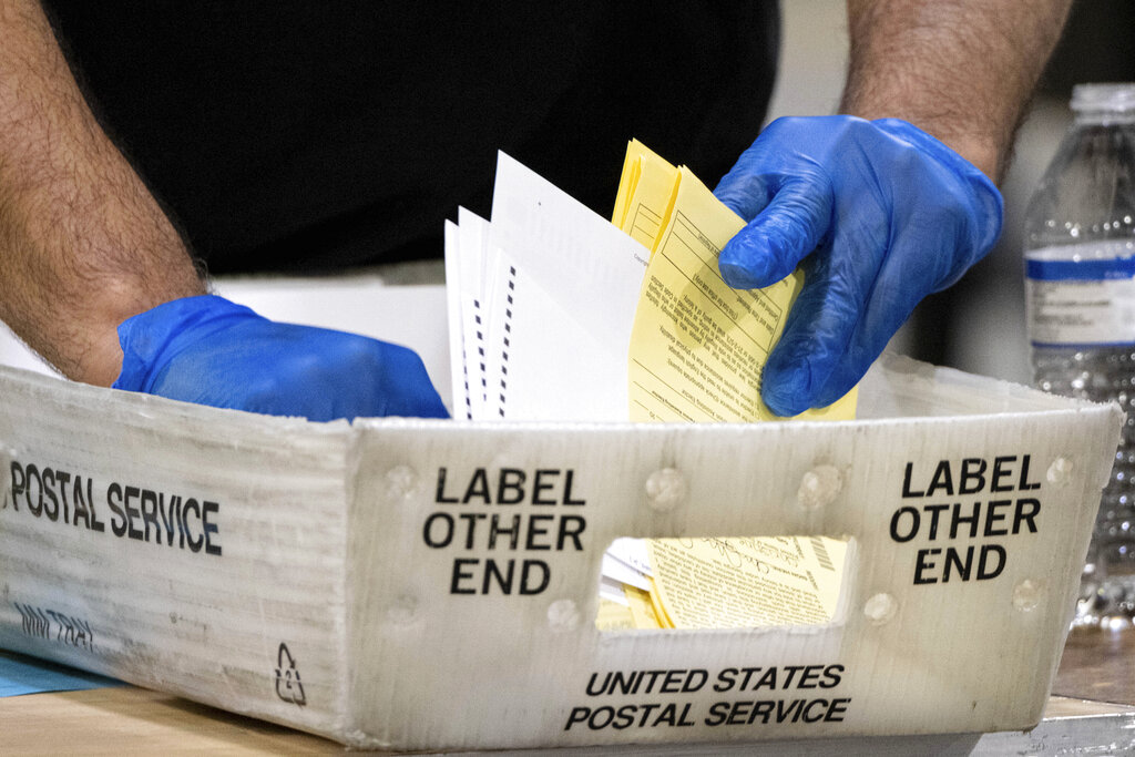 FILE - In this Jan. 5, 2021 file photo, Fulton County Georgia elections workers process absentee ballots for the Senate runoff election in Atlanta. When voters in Florida and Georgia request mailed ballots next year, they will have to make sure they do one more thing before sending it in: provide proof of identification. (AP Photo/Ben Gray, File)