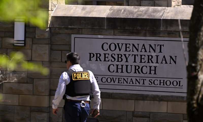 A police officer walks by an entrance to The Covenant School after a shooting in Nashville, Tenn. on Monday, March 27, 2023. (AP Photo/John Amis)