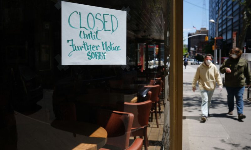 NEW YORK CITY- MAY 12: People walk through a shuttered business district in Brooklyn on May 12, 2020 in New York City. Across America, people are reeling from the loss of jobs and incomes as unemployment soars to historical levels following the COVID-19 outbreak. While some states are beginning to re-open slowly, many business are struggling to find a profit with the news restrictions and a population that is fearful of the contagious virus. (Photo by Spencer Platt/Getty Images)