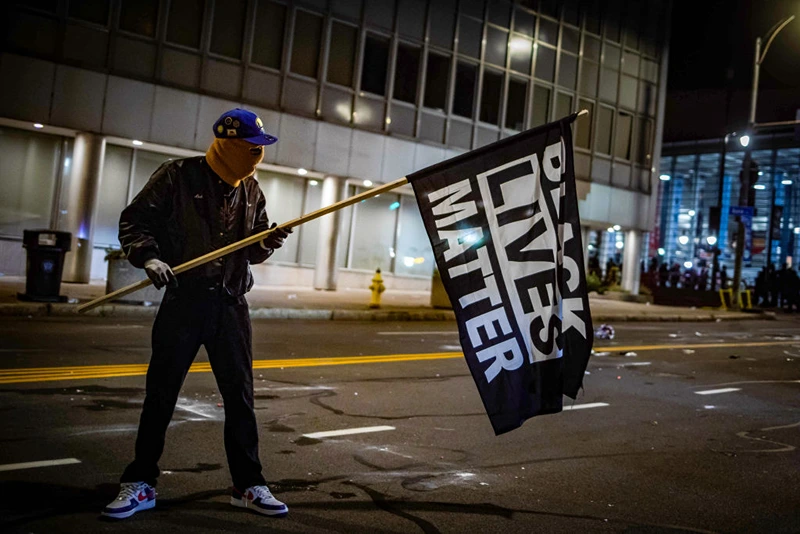 A protester wearing a Black Panther jacket and holding a "Black Lives Matter" flag faces off with riot police in Rochester, New York, on September 5, 2020 (Photo by MARANIE R. STAAB/AFP via Getty Images)
