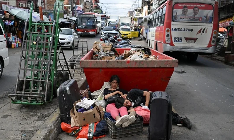 A bus with political advertising passes by a homeless couple sleeping on the street in Asuncion on April 26, 2023. - Paraguay holds general and presidential elections on April 30, 2023. (Photo by Luis ROBAYO / AFP) (Photo by LUIS ROBAYO/AFP via Getty Images)