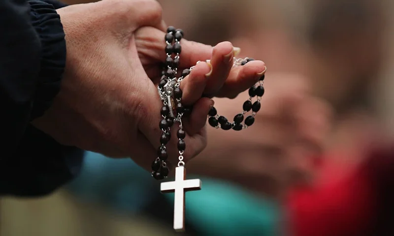 VATICAN CITY, VATICAN - MARCH 13: A woman holds rosary beads while she prays and waits for smoke to emanate from the chimney on the roof of the Sistine Chapel which will indicate whether or not the College of Cardinals have elected a new Pope on March 13, 2013 in Vatican City, Vatican. Pope Benedict XVI's successor is being chosen by the College of Cardinals in Conclave in the Sistine Chapel. The 115 cardinal-electors, meeting in strict secrecy, will need to reach a two-thirds-plus-one vote majority to elect the 266th Pontiff. (Photo by Dan Kitwood/Getty Images)