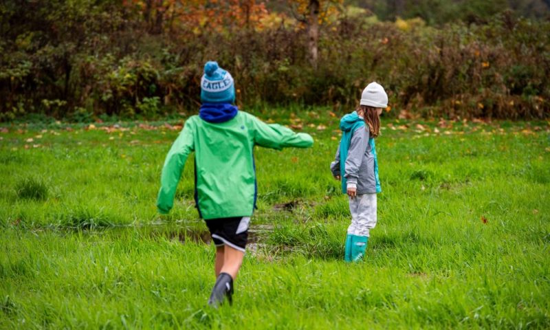 Brady and Morgan Cashman run around a muddy field by their new home in Stowe, Vermont on October 21, 2021. - Jessica Distefano still cries when she thinks about the fire that burned her out of her Californian home, and forced her to join the growing ranks of climate refugees in the world's richest country. "I just felt like I was raising my kids in a disaster zone. Everything around us was burnt," she tells AFP, three years after fleeing the town of Paradise as it was almost wiped off the map by a ferocious -- and deadly -- blaze. (Photo by JOSEPH PREZIOSO / AFP) (Photo by JOSEPH PREZIOSO/AFP via Getty Images)