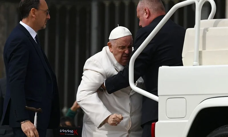 TOPSHOT - Pope Francis is helped get up the popemobile car as he leaves on March 29, 2023 at the end of the weekly general audience at St. Peter's square in The Vatican. - Pope Francis has been at the Gemelli Hospital in Rome since the afternoon of March 29, 2023 for some previously scheduled check-ups, the Holy See press director said. (Photo by Vincenzo PINTO / AFP) (Photo by VINCENZO PINTO/AFP via Getty Images)