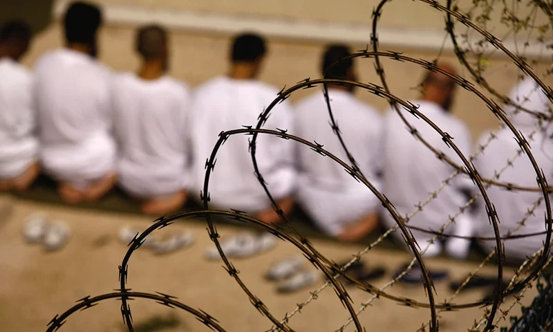 GUANTANAMO BAY, CUBA - OCTOBER 28: (EDITORS NOTE: Image has been reviewed by U.S. Military prior to transmission) A group of detainees kneels during an early morning Islamic prayer in their camp at the U.S. military prison for "enemy combatants" on October 28, 2009 in Guantanamo Bay, Cuba. Although U.S. President Barack Obama pledged in his first executive order last January to close the infamous prison within a year's time, the government has been struggling to try the accused terrorists and to transfer them out ahead of the deadline. Military officials at the prison point to improved living standards and state of the art medical treatment available to detainees, but the facility's international reputation remains tied to the "enhanced interrogation techniques" such as waterboarding employed under the Bush administration. (Photo by John Moore/Getty Images)
