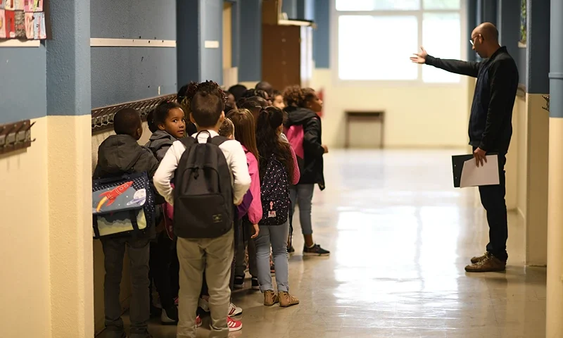A teacher speaks to his pupils in a corridor prior to enter in a classroom at a primary school at the start of the new school year on September 4, 2017, in Corbeil-Essonnes, outside Paris. (Photo by CHRISTOPHE SIMON / AFP) (Photo credit should read CHRISTOPHE SIMON/AFP via Getty Images)