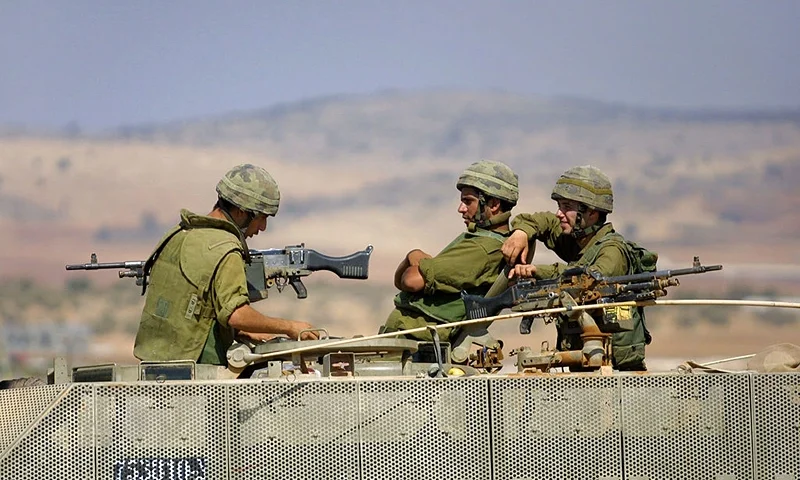 394703 04: Israeli soldiers pass the time sitting on the their armored personnel carrier September 20, 2001 on the Israeli side of the border of Jenin in the West Bank, two days after withdrawing from the Palestinian self-rule town. The ceasefire declared by both sides on Tuesday remained in effect despite the shooting death of an Israeli woman settler by Palestinian gunmen early in the day. (Photo by David Silverman/Getty Images)