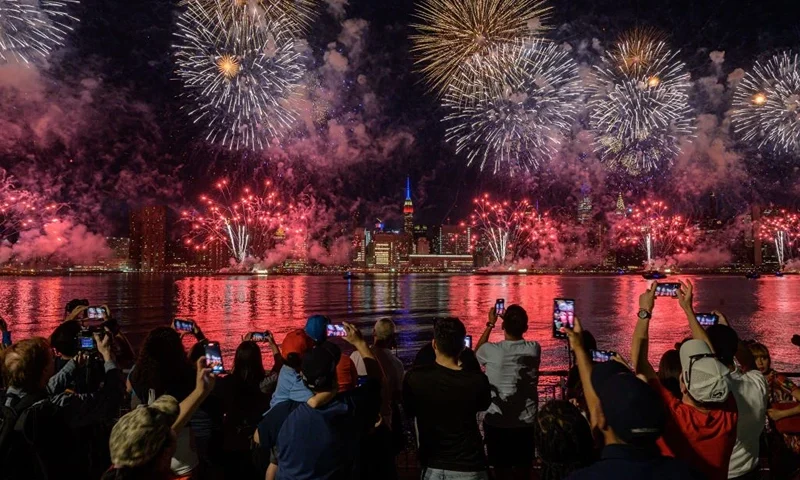 TOPSHOT - Spectators watch as fireworks explode over the Manhattan skyline during Independence Day celebrations in New York city on July 4, 2022. (Photo by Ed JONES / AFP) (Photo by ED JONES/AFP via Getty Images)
