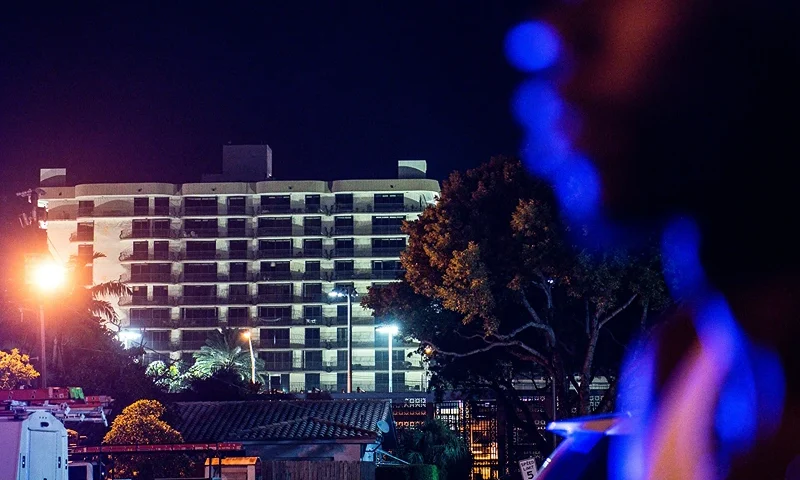 People wait to watch as the rest of the Champlain South tower is demolished by a controlled explosion in Surfside, Florida, north of Miami Beach, late on July 4, 2021. - A controlled explosion brought down the unstable remains of the collapsed apartment block in Florida late on July 4 ahead of a threatening tropical storm as rescuers prepare to resume searching for victims. (Photo by CHANDAN KHANNA / AFP) (Photo by CHANDAN KHANNA/AFP via Getty Images)