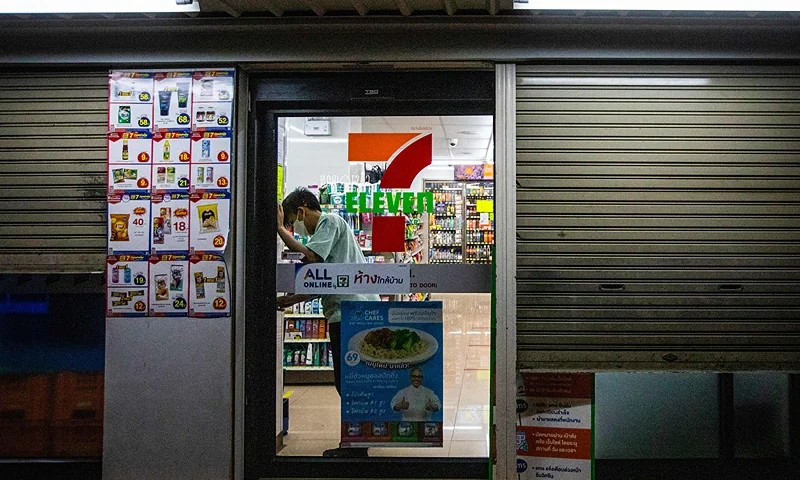 An employee of the 7-Eleven convenience store, which is usually open 24 hours, locks the door of the outlet in Bangkok on July 19, 2021, ahead of the night-time curfew restriction implemented to reduce the spread of the Covid-19 coronavirus. (Photo by Candida NG / AFP) (Photo by CANDIDA NG/AFP via Getty Images)