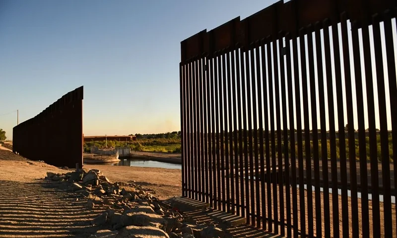 The sun sets behind a gap along the border wall at the Morelos Dam between the US and Mexico in Yuma, Arizona on May 31, 2022. - The stream of impoverished humans flowing into the United States via Mexico runs through the country's public discourse, dividing its politics and coloring relations with nations to the south. The issue of migration is set to loom large at the Summit of the Americas in Los Angeles this week, even without the presence of Mexican President Andres Manuel Lopez Obrador, who is boycoting the meet in protest at the exclusion of Venezuela, Nicaragua and Cuba. (Photo by Patrick T. FALLON / AFP) (Photo by PATRICK T. FALLON/AFP via Getty Images)