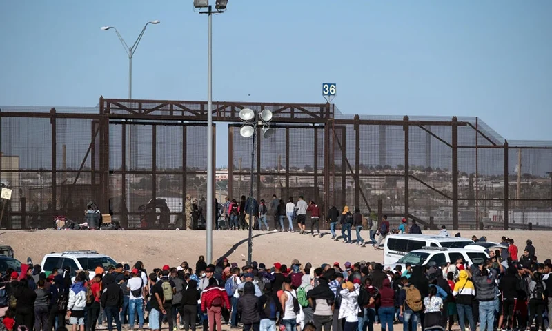 TOPSHOT - Migrants are processed by United States border patrol agents seen from the Mexican side of the US-Mexico border in Ciudad Juarez, Chihuahua state, Mexico, on March 29, 2023. - About 200,000 people try to cross the border from Mexico into the United States each month, most of them fleeing poverty and violence in Central and South America. (Photo by Guillermo Arias / AFP) (Photo by GUILLERMO ARIAS/AFP via Getty Images)