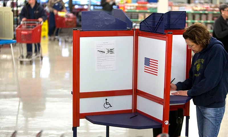 DUBUQUE, IA - NOVEMBER 6: With customers rolling by with shopping carts, Robin Sanford of Dubuque, Iowa casts her ballot at her polling location in the Theisens Store on November 6, 2012 in Dubuque, Iowa. U.S. citizens go to the polls today to vote in the election between Democratic President Barack Obama and Republican nominee former Massachusetts Gov. Mitt Romney. (Photo by Mark Hirsch/Getty Images)