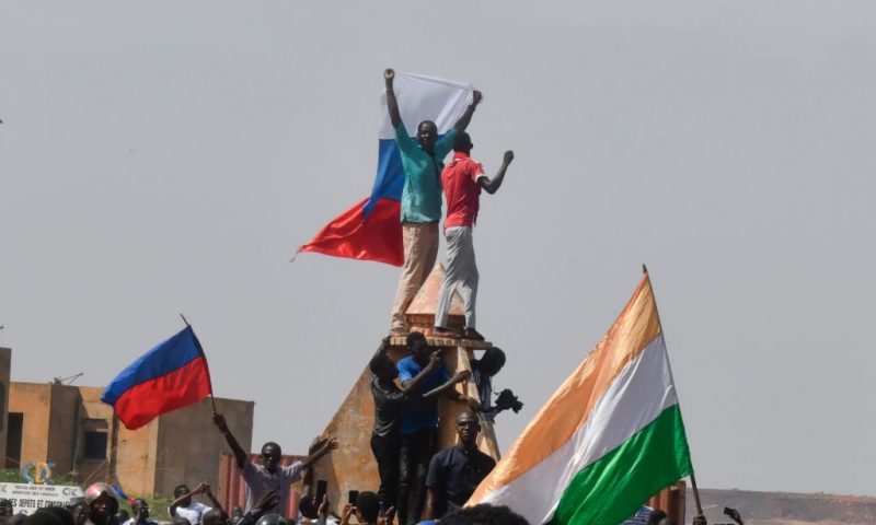 Protesters wave Nigerien and Russian flags as they gather during a rally in support of Niger's junta in Niamey on July 30, 2023. Thousands of people demonstrated in front of the French embassy in Niamey on Sunday, before being dispersed by tear gas, during a rally in support of the military putschists who overthrew the elected president Mohamed Bazoum in Niger. Before the tear-gas canisters were fired, a few soldiers stood in front of the embassy to calm the demonstrators. (Photo by AFP) (Photo by -/AFP via Getty Images