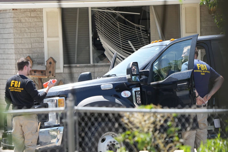 PROVO, UTAH - AUGUST 9: With a broken window in the background, FBI agents process the home of Craig Robertson who was shot and killed by the FBI in a raid on his home this morning on August 9, 2023 in Provo, Utah. The FBI was investigating alleged threats by Robertson to President Biden who is visiting Salt Lake City today and tomorrow. (Photo by George Frey/Getty Images)
