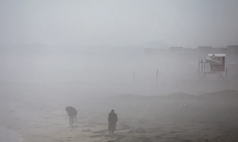 IMPERIAL BEACH, CALIFORNIA - AUGUST 20: People walk in the rain along the Pacific Ocean with Tropical Storm Hilary approaching in San Diego County on August 20, 2023 in Imperial Beach, California. Southern California is under a first-ever tropical storm warning as Hilary approaches with parts of California, Arizona and Nevada preparing for flooding and heavy rains. All California state beaches have been closed in San Diego and Orange counties in preparation for the impacts from the storm which was downgraded from hurricane status. (Photo by Mario Tama/Getty Images)