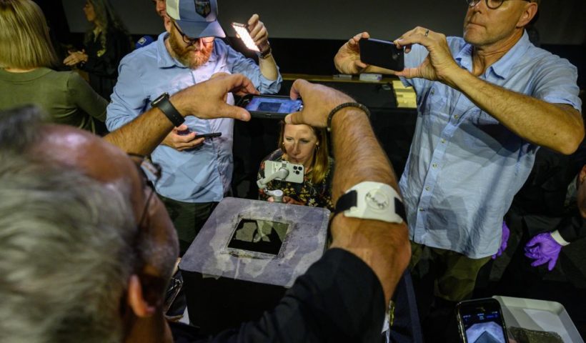 TOPSHOT - People gather around a nearly 200-year-old time capsule during a ceremony in the Robinson Auditorium at Thayer Hall of the US Military Academy in West Point, New York, on August 28, 2023. The sealed lead time capsule measuring about one square foot was discovered in the Thaddeus Kosciuszko monument's base during recent renovations. Academy officials determined the capsule was placed in the base of the Kosciuszko monument 26 years after the academy's founding by cadets in 1828. The capsule was found to be mostly empty other than grey sediment. (Photo by Ed JONES / AFP) (Photo by ED JONES/AFP via Getty Images)
