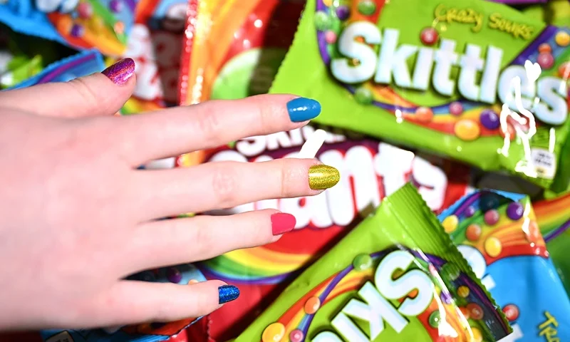 LIVERPOOL, ENGLAND - MAY 11: A general view of a hand reaching for various flavoured bags of Skittles during the 'Queer Joy' exhibition preview on May 11, 2023 in Liverpool, England. Popping up in Liverpool's iconic Royal Albert Dock, the exhibition will explore the concept of 'Queer Joy' - defined as the deep happiness that brings warmth & purpose to queer lives. (Photo by Shirlaine Forrest/Getty Images for GAY TIMES x Skittles)