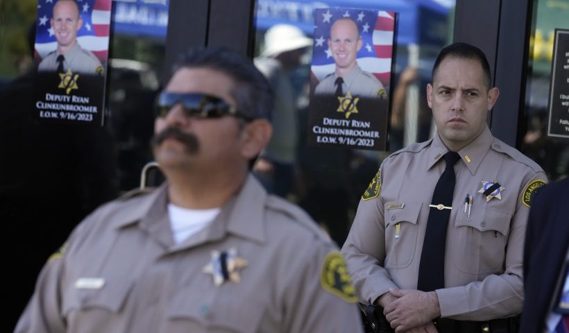 Photos of Los Angeles County sheriffs deputy Ryan Clinkunbroomer are placed at the entrance of the Palmdale Sheriff's Station during a press to announce an arrest in the ambush killing of Clinkunbroomer Monday, Sept. 18, 2023, in Palmdale, Calif. Clinkunbroomer was shot and killed while sitting in his patrol car Saturday evening in Palmdale. (AP Photo/Marcio Jose Sanchez)
