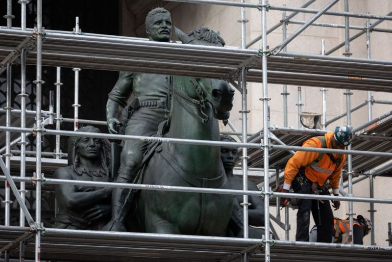 Construction workers erect scaffolding around the statue of US President Theodore Roosevelt at the American Museum of Natural History in New York City on December 2, 2021. - New York has begun the extended process of removing a statue of former US president Theodore Roosevelt, which has been long criticized as a racist and colonialist symbol and became a cultural flashpoint in recent years. The statue depicts Roosevel on horseback with Native American and African American figures standing at his side. (Photo by Yuki IWAMURA / AFP) (Photo by YUKI IWAMURA/AFP via Getty Images)