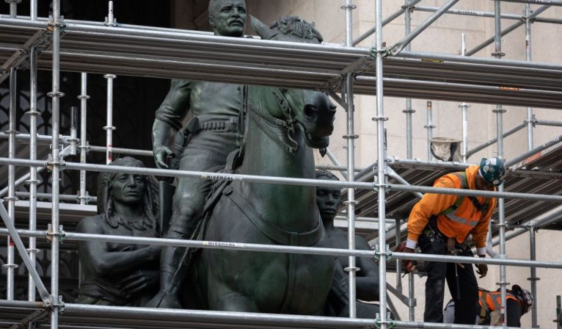 Construction workers erect scaffolding around the statue of US President Theodore Roosevelt at the American Museum of Natural History in New York City on December 2, 2021. - New York has begun the extended process of removing a statue of former US president Theodore Roosevelt, which has been long criticized as a racist and colonialist symbol and became a cultural flashpoint in recent years. The statue depicts Roosevel on horseback with Native American and African American figures standing at his side. (Photo by Yuki IWAMURA / AFP) (Photo by YUKI IWAMURA/AFP via Getty Images)
