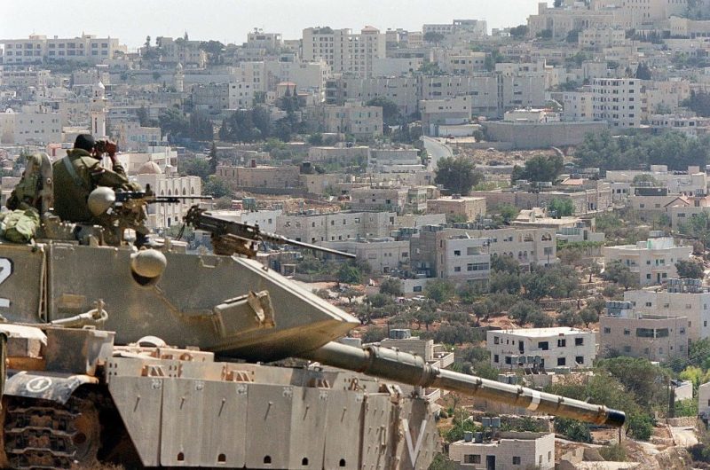 Israeli soldiers take position with their tank on the hills of Beit Jala overlooking the West Bank town of Bethlehem 08 October 2000. Israeli officials including Prime Minister Ehud Barak, warned of strong action by Israeli forces if the violence that has shaken the Palestinian territories for 10 days does not end by 09 October. (Photo by PATRICK BAZ / AFP) (Photo by PATRICK BAZ/AFP via Getty Images)