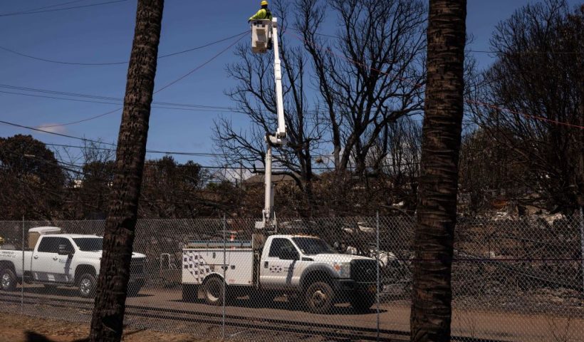 A Hawaiian Electric employee repairs power lines in the aftermath of the Maui Fires in Lahaina, West Maui, Hawaii, August 17, 2023. Embattled officials in Hawaii who have been criticized for the lack of warnings as a deadly wildfire ripped through a town insisted on August 16 that sounding emergency sirens would not have saved lives. At least 110 people died when the inferno levelled Lahaina last week on the island of Maui, with some residents not aware their town was at risk until they saw flames for themselves. (Photo by Yuki IWAMURA / AFP) (Photo by YUKI IWAMURA/AFP via Getty Images)