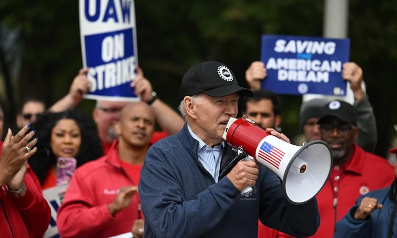TOPSHOT-US-POLITICS-AUTOMOBILE-UNIONS-STRIKE-BIDEN-economy-labou TOPSHOT - US President Joe Biden addresses striking members of the United Auto Workers (UAW) union at a picket line outside a General Motors Service Parts Operations plant in Belleville, Michigan, on September 26, 2023. Some 5,600 members of the UAW walked out of 38 US parts and distribution centers at General Motors and Stellantis at noon September 22, 2023, adding to last week's dramatic worker walkout. According to the White House, Biden is the first sitting president to join a picket line. (Photo by Jim WATSON / AFP) (Photo by JIM WATSON/AFP via Getty Images)