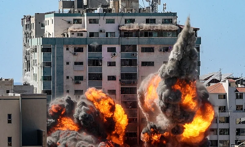 TOPSHOT - A ball of fire erupts from the Jala Tower as it is destroyed in an Israeli airstrike in Gaza City, controlled by the Palestinian Hamas movement, on May 15, 2021. - Israeli air strikes pounded the Gaza Strip, killing 10 members of an extended family and demolishing a key media building, while Palestinian militants launched rockets in return amid violence in the West Bank. Israel's air force targeted the 13-floor Jala Tower housing Qatar-based Al-Jazeera television and the Associated Press news agency. (Photo by Mahmud Hams / AFP) (Photo by MAHMUD HAMS/AFP via Getty Images)