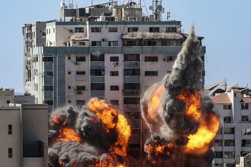 TOPSHOT - A ball of fire erupts from the Jala Tower as it is destroyed in an Israeli airstrike in Gaza City, controlled by the Palestinian Hamas movement, on May 15, 2021. - Israeli air strikes pounded the Gaza Strip, killing 10 members of an extended family and demolishing a key media building, while Palestinian militants launched rockets in return amid violence in the West Bank. Israel's air force targeted the 13-floor Jala Tower housing Qatar-based Al-Jazeera television and the Associated Press news agency. (Photo by Mahmud Hams / AFP) (Photo by MAHMUD HAMS/AFP via Getty Images)