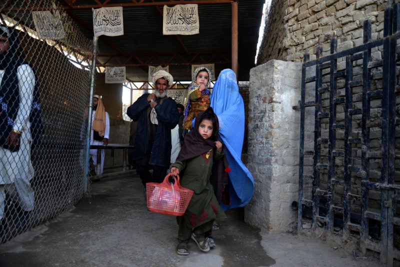 TOPSHOT - In this picture taken on November 21, 2022, Afghans walk along a fenced corridor as they cross into Pakistan at the Afghanistan-Pakistan border in Spin Boldak. (Photo by AFP) (Photo by -/AFP via Getty Images)