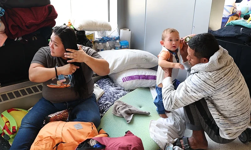 CHICAGO, ILLINOIS - MAY 09: A migrant couple from Venezuela and their 15-month-old son rest in the lobby of a police station where they have been staying with other migrant families since their arrival to the city on May 09, 2023 in Chicago, Illinois. Chicago Mayor Lori Lightfoot issued a state of emergency on Tuesday amid a surge in migrant arrivals which began in August 2022 when the first group of immigrants were bused from Texas to Chicago by Texas Gov. Greg Abbott. According to Lightfoot's office, more than 8,000 migrants have arrived in Chicago since last year, with the city currently reaching "a breaking point." About 500 migrants have reportedly been living in the lobbies of police precincts around the city where they sleep on the floors and rely on food donations. (Photo by Scott Olson/Getty Images)