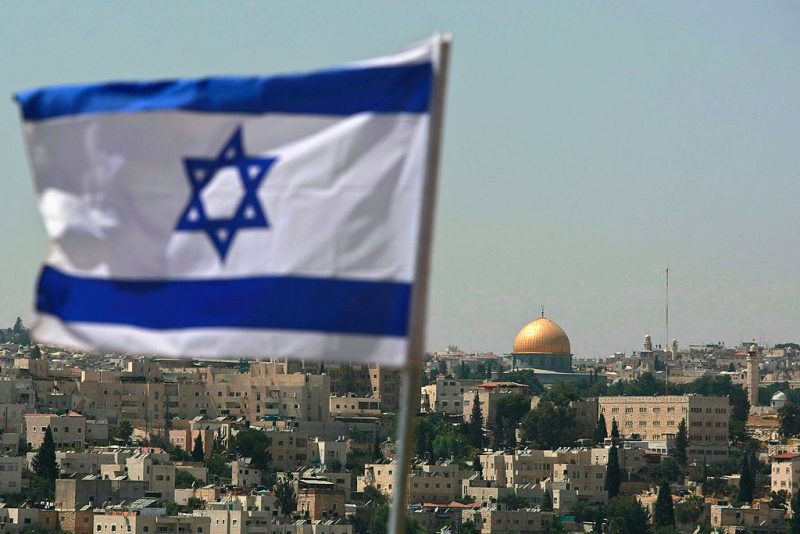 JERUSALEM - AUGUST 18: An Israeli flag flies from the Kidmat Zion Jewish settlement community on the outskirts of the Arab village of Abu Dis, where the Old City with its golden Dome of the Rock Islamic shrine is seen in the background, August 18, 2008 in East Jerusalem, Israel. The settlement, a stand-alone apartment building which houses a number of families, is a former Arab home purchased by the Ateret Cohanim organization which is dedicated to expanding Jewish settlement in East Jerusalem, the half of the city that Israel captured from Jordan in the 1967 Six Day War. (Photo by David Silverman/Getty Images)