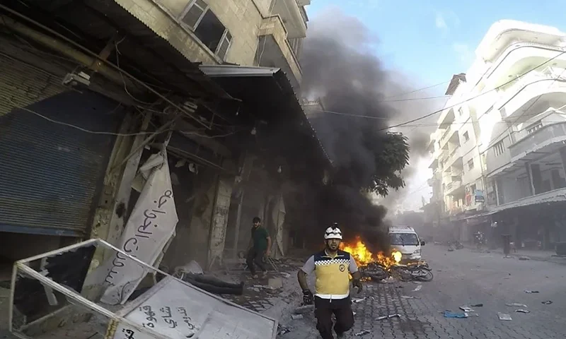 7 of 11 | In this photo provided by the Syrian Civil Defense White Helmets, a Syrian White Helmet civil defense worker runs at the site where a shell struck in the outskirts of the northern town of Jisr al-Shoughour, west of the city of Idlib, Syria, Thursday, Oct. 5, 2023. A drone attack struck a packed graduation ceremony for military officers in the Syrian city of Homs on Thursday, killing and wounding dozens reports said. Following the drone attack, the government shelled villages in Idlib province, in the rebel-held northwestern part of the country. (Syrian Civil Defense White Helmets via AP)