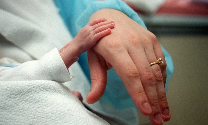 FRANCE-NEONATOLOGY-MEDICINE-PREMATURE A premature baby poses on February 20, 2003, his hand on his mother's in the neonatology department of Robert Debré hospital in Paris. - Very premature infants are referred to this specialized intensive care unit because resuscitation is particularly cumbersome and sometimes accompanied by complications. A premature baby is a child born before the 37th week (8 months or 259 days) and whose all major functions are immature (respiratory, immune, digestive). Approximately 44,000 children are born prematurely each year in France. Prematurity thus reaches 5.9% of births in France. AFP PHOTO DIDIER PALLAGES (Photo by Didier PALLAGES / AFP) (Photo credit should read DIDIER PALLAGES/AFP via Getty Images)
