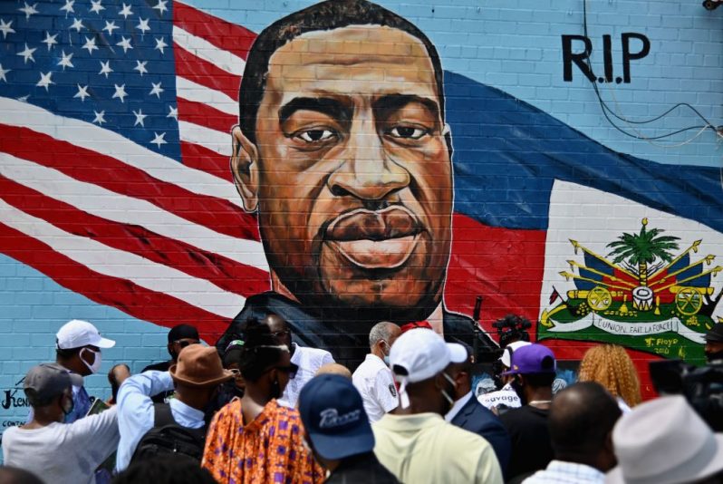 TOPSHOT - People gather at the unveiling of artist Kenny Altidor's memorial portrait of George Floyd - who died 25 May in Minneapolis with police officer Derek Chauvin kneeling on his neck for nearly nine minutes - painted on a storefront sidewall of CTown Supermarket on July 13, 2020 in Brooklyn, New York. (Photo by Angela Weiss / AFP) / RESTRICTED TO EDITORIAL USE - MANDATORY MENTION OF THE ARTIST UPON PUBLICATION - TO ILLUSTRATE THE EVENT AS SPECIFIED IN THE CAPTION (Photo by ANGELA WEISS/AFP via Getty Images)