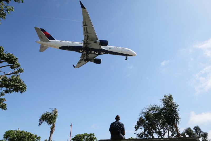 LOS ANGELES, CA - JULY 12: A man watches as a Delta Air Lines plane lands at Los Angeles International Airport on July 12, 2018 in Los Angeles, California. Delta announced today that it will increase fares by reducing the supply of seats in an effort to offset higher fuel prices. (Photo by Mario Tama/Getty Images)