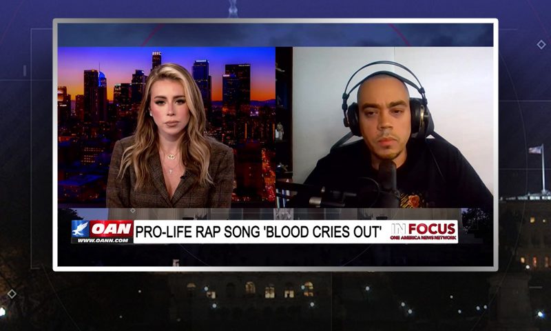 Video still from In Focus on One America News Network showing a split screen of the host on the left side, and on the right side is the guest, Communion.