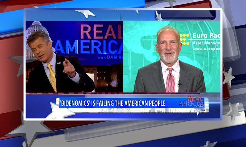 Video still from Real America on One America News Network showing a split screen of the host on the left side, and on the right side is the guest, Peter Schiff.