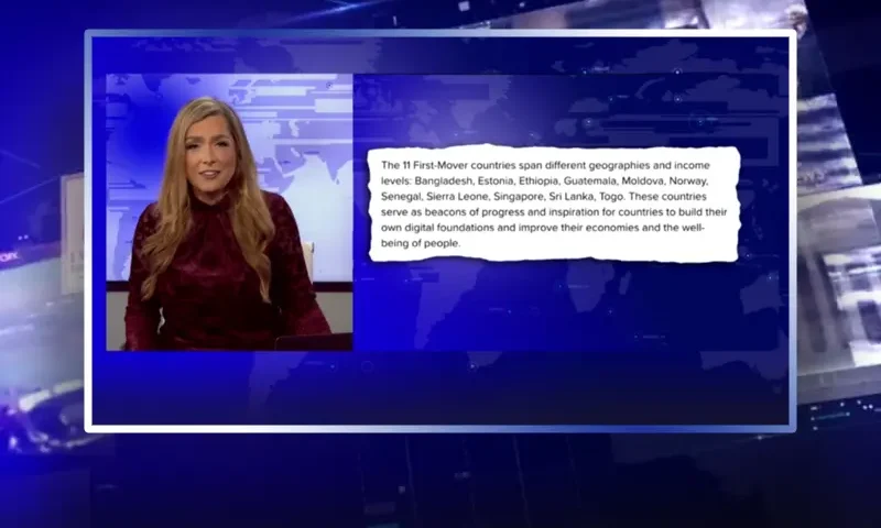 Video still of the host of The Real Story at the desk of their talk show on One America News Network.