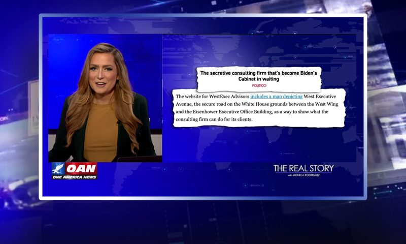 Video still of the host of The Real Story at the desk of their talk show on One America News Network.