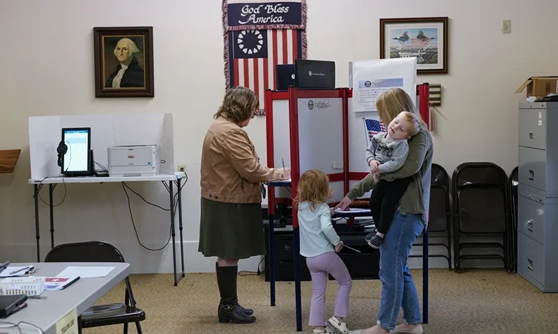 Lauren Miracle, right, holds her son Dawson, 1, as she helps her daughter Oaklynn, 3, fill out a child's practice ballot before voting herself at a polling location in the Washington Township House in Oregonia, Ohio, Tuesday, Nov. 7. Polls are open in a few states for off- year elections that could give hints of voter sentiment ahead of next year's critical presidential contest. (AP Photo/Carolyn Kaster)