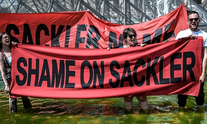 TOPSHOT - Activists of P.A.I.N. (Prescription Addiction Intervention Now) association - created to respond to the opioid crisis - and of French NGO Aides hold banners reading "Shame on Sackler" and "Take down the Sackler name" (back) in front of the Pyramid of the Louvre museum (Pyramide du Louvre), on July 1, 2019 in Paris, during a protest to condemn the museum's ties with the Sackler family, billionaire donors accused of pushing to sell a highly addictive painkiller blamed for tens of thousands of deaths. - The Sacklers have been high-profile philanthropists to cultural institutions such as the Tate in London and the Guggenheim in New York, but museums and galleries have recently been rebuffing their donations because of the opioid crisis fallout. The most recent museum to cut ties with the Sackler family is New York's Metropolitan Museum, which announced earlier this month that it will cease accepting gifts from the family. (Photo by STEPHANE DE SAKUTIN / AFP) (Photo by STEPHANE DE SAKUTIN/AFP via Getty Images)