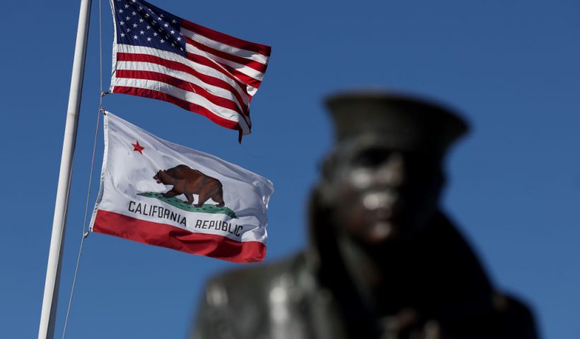 SAUSALITO, CALIFORNIA - OCTOBER 24: An American flag flies with the California State flag next to the Lone Sailor statue on October 24, 2022 in Sausalito, California. The State of California, currently the fifth largest economy in the world, is likely to overtake Germany as the fourth largest economy in the near future as the state's gross domestic product is continuing to rise with steady growth. (Photo by Justin Sullivan/Getty Images)