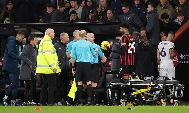 AFC Bournemouth v Luton Town - Premier League BOURNEMOUTH, ENGLAND - DECEMBER 16: Referee Simon Hooper is handed the match ball by Philip Billing of AFC Bournemouth as players of Luton Town and AFC Bournemouth leave the field as Tom Lockyer of Luton Town (not pictured) receives medical treatment after collapsing during the Premier League match between AFC Bournemouth and Luton Town at Vitality Stadium on December 16, 2023 in Bournemouth, England. (Photo by Warren Little/Getty Images)