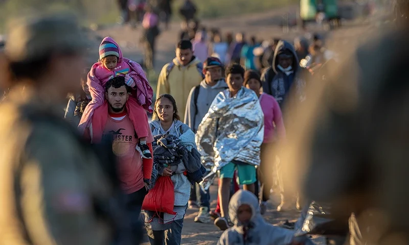 EAGLE PASS, TEXAS - DECEMBER 19: Texas National Guard soldiers observe as thousands of immigrants walk towards a U.S. Border Patrol transit center on December 19, 2023 in Eagle Pass, Texas. Most had crossed the border from Mexico the night before. A major surge of migrants illegally crossing the Rio Grande have overwhelmed U.S. border authorities in recent weeks. (Photo by John Moore/Getty Images)