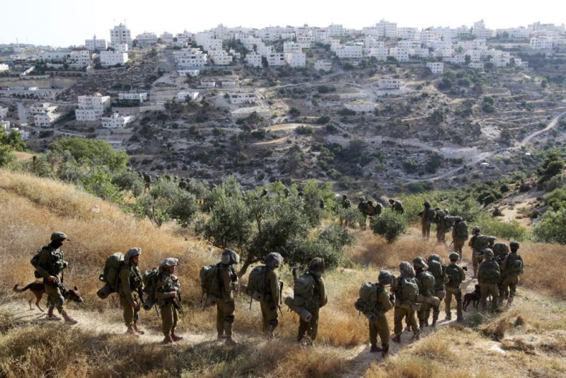 TOPSHOT - Israeli soldiers walk in a single file on a path during an operation in the West Bank town of Hebron on June 17, 2014 as Israeli forces broadened the search for three teenagers believed kidnapped by militants and imposed a tight closure of the town. Israeli Prime Minister Benjamin Netanyahu demanded Palestinian president Mahmud Abbas's help in securing the release of three kidnapped teenagers, as the army launched a massive crackdown on Islamist movement Hamas. AFP PHOTO/ HAZEM BADER (Photo by HAZEM BADER / AFP) (Photo by HAZEM BADER/AFP via Getty Images)