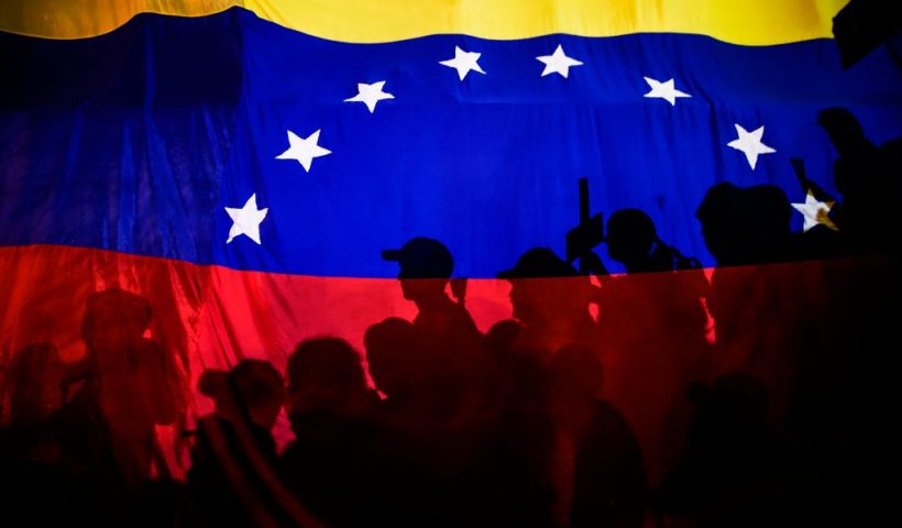 TOPSHOT - Opposition activists, seen here behind a Venezuelan flag, protest against the deaths of 43 people in clashes with the police during weeks of demonstrations against the government of Venezuelan President Nicolas Maduro, in Caracas on May 17, 2017. - The United States warned on Wednesday at the United Nations that Venezuela's crisis was worsening and could escalate into a major conflict similar to Syria or South Sudan. (Photo by JUAN BARRETO / AFP) (Photo by JUAN BARRETO/AFP via Getty Images)