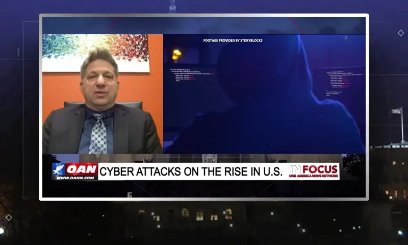 Video still from In Focus on One America News Network showing a split screen of the host on the left side, and on the right side is the guest, John Guandolo.