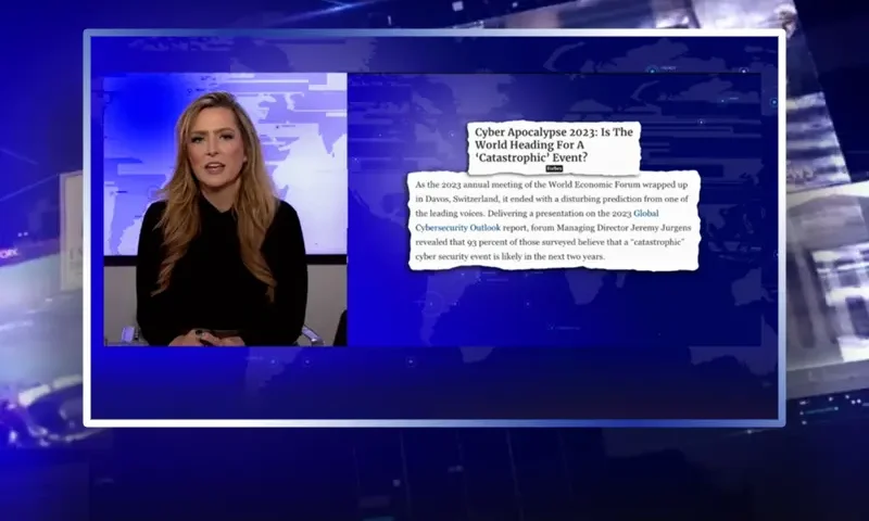 Video still of the host of The Real Story at the desk of their talk show on One America News Network.
